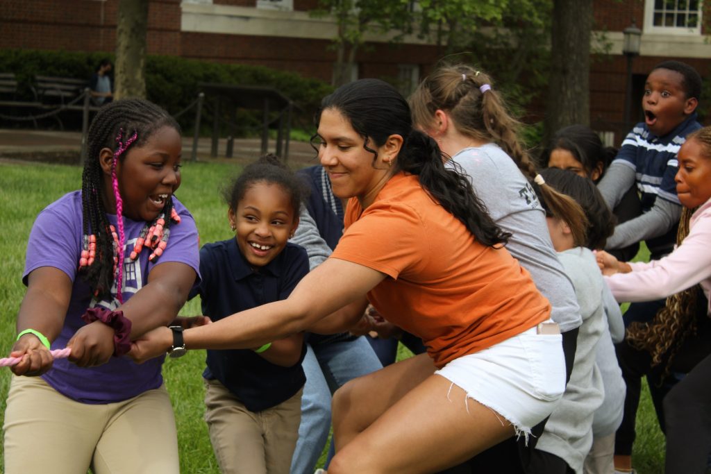 Tutor pulling on the rope alongside tutees at the 2023 field day
